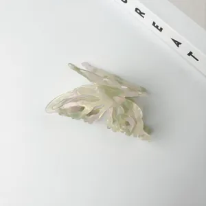 Detailed view of an iridescent green acetate butterfly hair claw clip with cutout wings