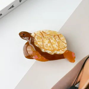 Détail d'une pince à cheveux tortue avec texture acétate écaille et lignes dorées