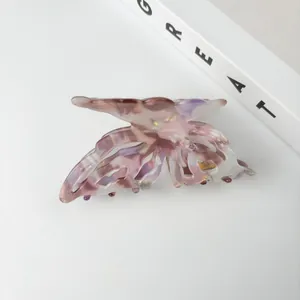 Close-up of a pink marble acetate butterfly hair claw clip on a clean white background