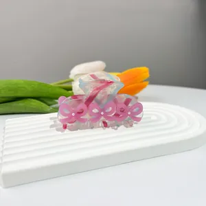 Dettaglio della molletta in acetato con fiocchi rosa e perline su base in pietra