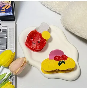 Macro detail of cute acetate hair claws in beverage and sun hat shapes on a ceramic tray