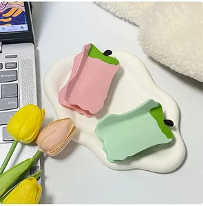 Detail of pink and green chili-shaped acetate hair claws on a ceramic plate