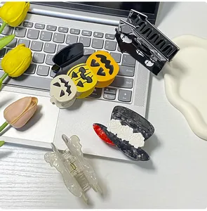 Variety of Halloween pumpkin and ghost themed hair claws displayed on a modern desk setup
