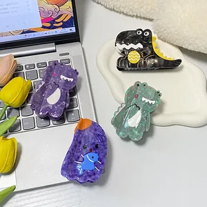 Cute cartoon dinosaur and monster acetate hair claws in various colors on a tray