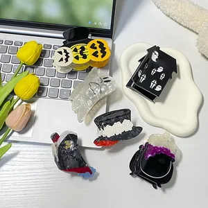 Halloween claw clips set with pumpkin, ghost, and bat designs on a white desk background