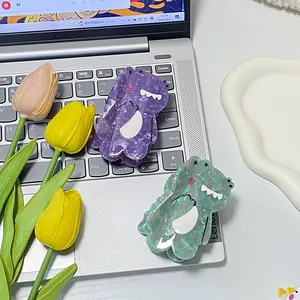 Cute cartoon dinosaur acetate hair claws in purple and green on a laptop keyboard