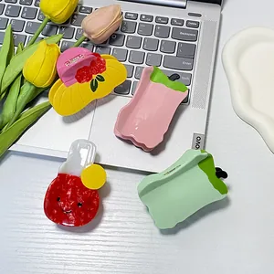 Set of four colorful acetate hair claws in playful shapes like hats and fruit designs