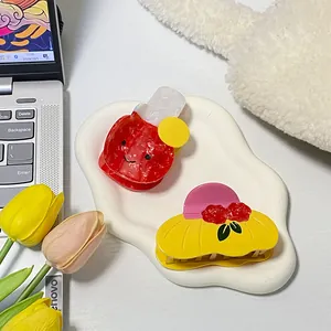 Set of 2 cute acetate hair claws with smiley apple and polka dot patterns on a tray