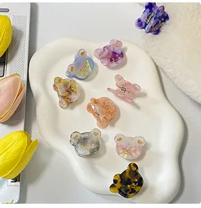 Mini-Haarklammern aus Acetat in Bärenform mit Marmormuster auf einer weißen Keramikschale