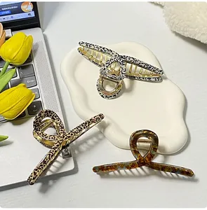 Three acetate leopard and tortoiseshell hair claws displayed on a white tray with flowers