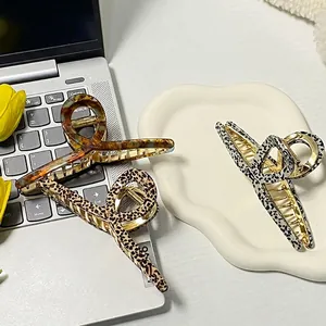 Three large acetate hair claws in leopard and amber patterns on a ceramic tray