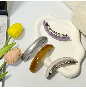 Set of four glossy marble-textured arc hair clips on a white ceramic display tray