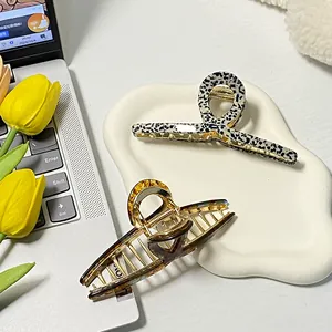 Polka dot and tortoise shell acetate hair claws on a ceramic tray with tulips