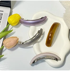 Detail of four colorful arc-shaped hair clips in violet, grey, amber and pink finishes