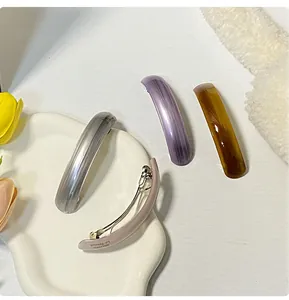 Close-up of four assorted pearlized hair barrettes in a ceramic dish with tulips
