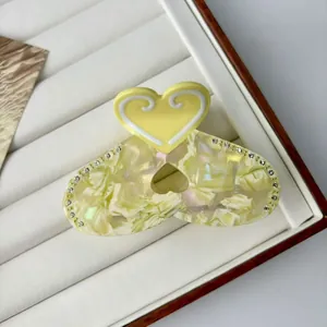 Elegant yellow heart acetate hair claw clip with rhinestones and marble texture detail
