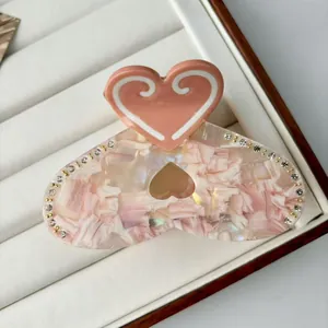 Macro shot of pink marble acetate hair claw clip with heart handle and rhinestones