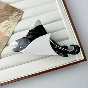 Macro detail of manta ray shaped acetate hair claw clip with black white marble texture