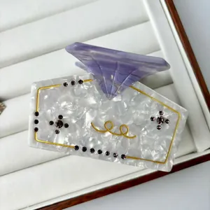 Detail der Acetat-Haarklammer mit goldenen Spiralmustern und violettem Strass-Kreuz-Dekor