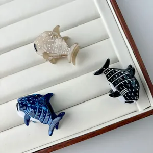 Three acetate whale shark hair claws in amber, deep blue, and black on a display tray