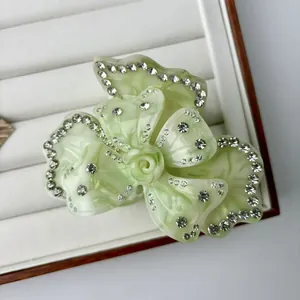 Detalle de la pinza de pelo de acetato verde claro con forma de flor y diamantes