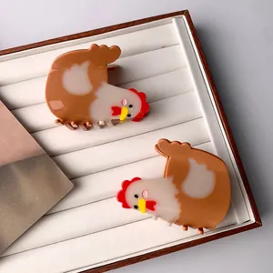Cute hen-shaped acetate hair claws in brown and cream tones on a white display tray