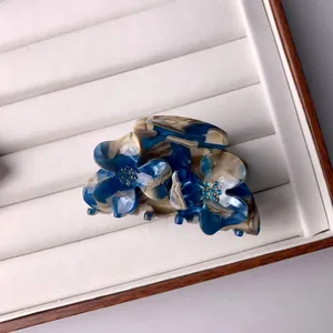 Gros plan d'une pince à cheveux fleurie en acétate marbré bleu avec détails en strass