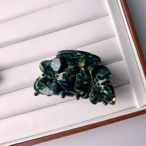 Détail de la pince à cheveux en acétate vert marbré avec motif de trois fleurs élégantes