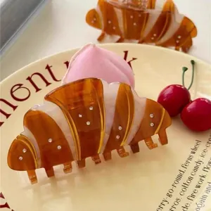 French croissant hair claw clip with diamonds and amber stripes on cream plate