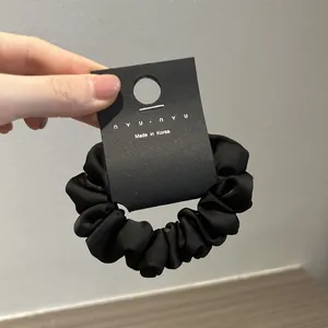 Vista dettagliata di un elastico in raso nero liscio con un cartellino del marchio appeso