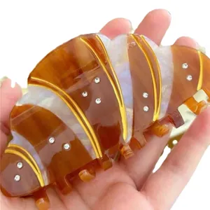 Chic croissant-shaped hair claw clip with rhinestones and amber pearl finish