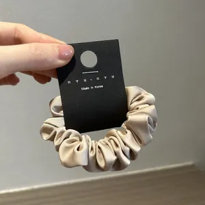 Dettaglio dell'elastico in raso color oro champagne con finitura lucida e cartellino