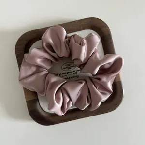 Close-up of French style satin hair scrunchie in dusty rose on a wooden tray decor