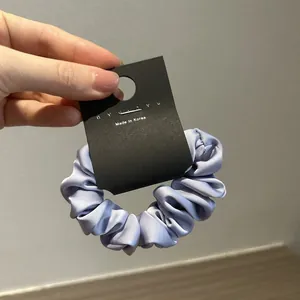 Dettaglio di un elastico per capelli in raso lavanda con una texture setosa e lucida