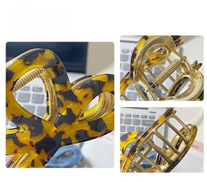 Detail view of tortoiseshell acetate claw clip showing strong golden metal spring and teeth