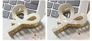 Detailed comparison of two acetic acid hair claws in cream and pearl white with metal teeth