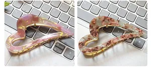 Detail of heart-shaped acetate claw clips in marble and amber textures with gold metal frame