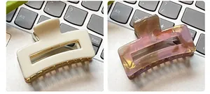 Detail view of small square claw clips in solid beige and marble pattern for hair styling