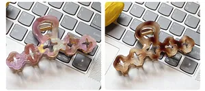 Detail of hollow four-leaf clover hair claws in marble pink and amber brown acetate