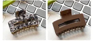 Detail of square hair claws in marble texture and matte brown on a laptop keyboard