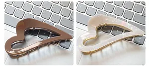 Close-up of hollow heart-shaped acetate hair claws in glossy brown and pearly white