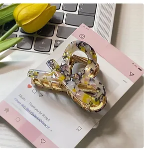 Detail of artistic acetate hair claw clip with colorful floral pattern and golden metal spring