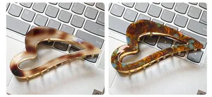 Detail view of acetate heart hair claws with marble and tortoiseshell patterns on metal base