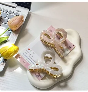 Detailed view of marble pink and pearly white acetate butterfly hair claws on a tray