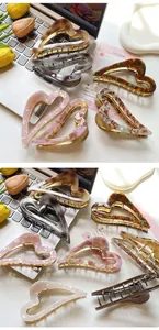 Close-up of heart-shaped acetate claw clips with marble texture and gold metal base