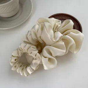 Elegant cream satin hair scrunchies in two sizes with smooth silk texture and pearl luster