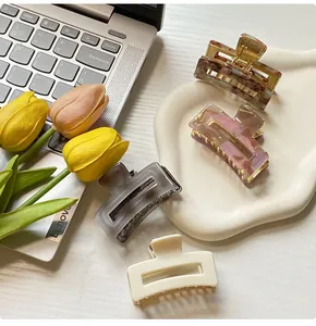 Close-up of four minimalist resin hair claws in assorted marble textures on a white tray