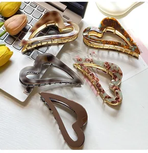 Detail of five heart-shaped acetate hair claws in tortoise and marble patterns