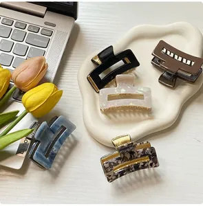 Close-up of small square hair claws in five colors with golden metal hinges