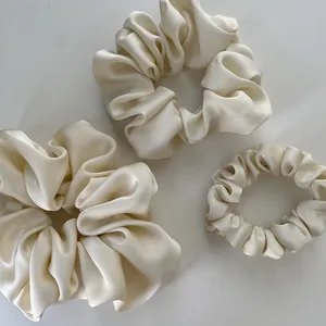 Three-piece set of cream satin scrunchies in various sizes with elegant silk luster